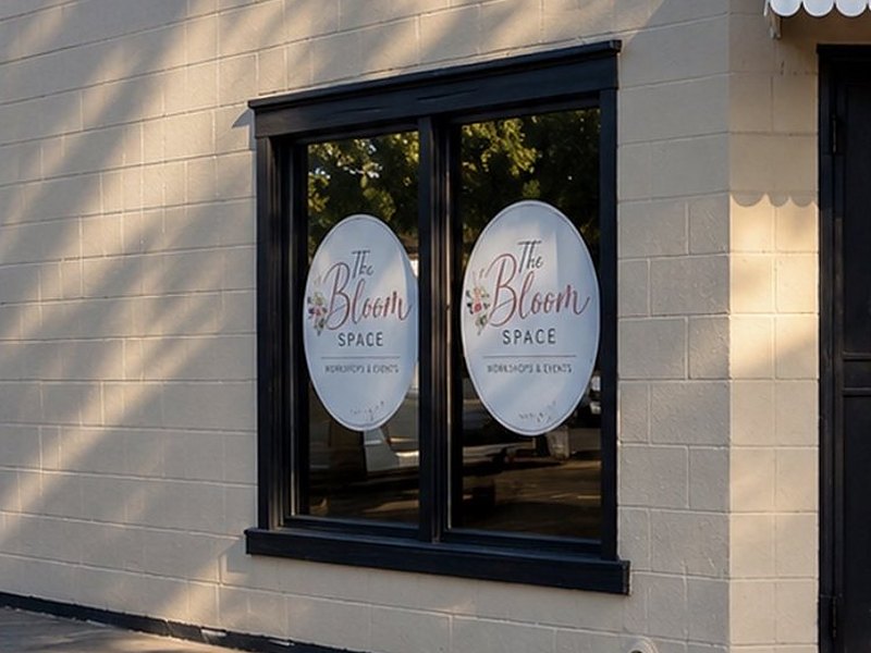 The Bloom Space logo on the two front windows, with afternoon tree shadows across the wall